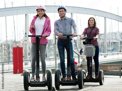Girls and guy traveling through city by segways