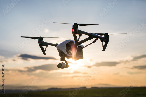 quadrocopter drone with remote control. Dark silhouette against colorfull sunset.