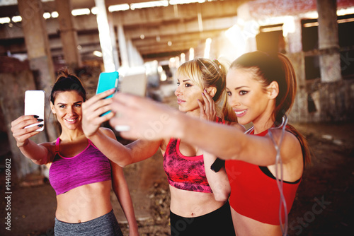 Group of fitness females taking selfies before training.