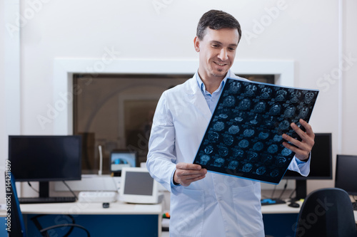 Pleasant delighted radiologist looking at the MRI scan results