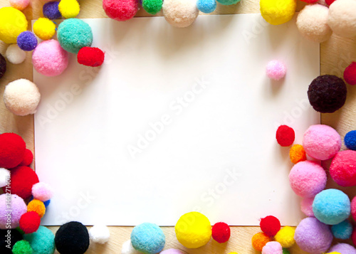 Frame of colorful pompons for creativity on a wooden background
