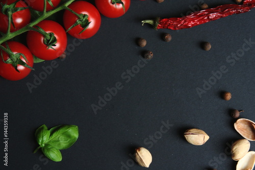 Czerwone, dojrzałe pomidory koktajlowe na gałązce na czarnym tle