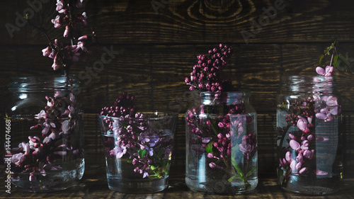 Picturesque purple spring flowers in glass vases standing in a row on a dark wooden background. Close up 