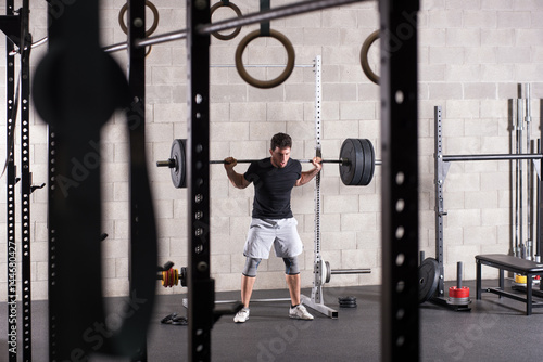 Man lifting heavy barbell on squat rack
