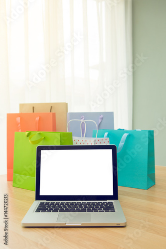 colorful paper shopping bags and laptop computer at home