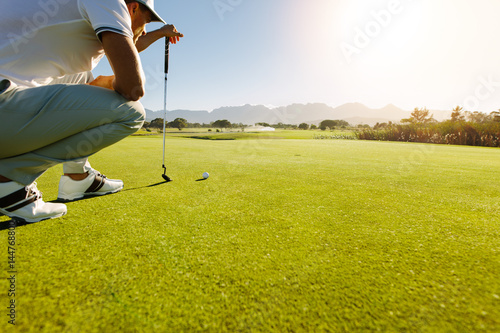 Pro golf player aiming shot with club on course