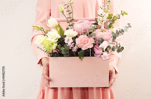 Pink wooden box with flowers roses and carnations in girl's hands