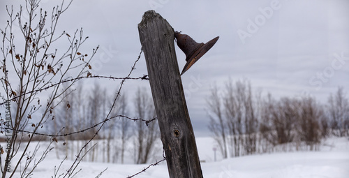 Old, rusty lantern on a fence with barbed wire. Lamp post and barbed wire in a concentration camp.