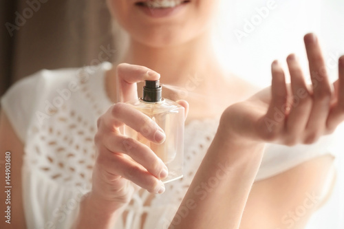 Piękna młoda kobieta z butelką pachnidło w domu, zbliżenie