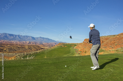 Rear view of a man playing golf on a Sunny day on a beautiful desert golf course in the Southwestern United states.