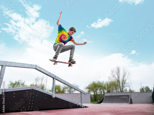 Skater jumping over handrail in skatepark