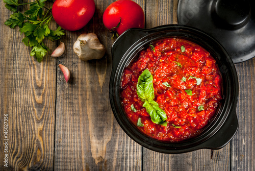 Basic Italian tomato sauce marinara for pasta. In a saucepot pan with ingredients on a wooden table. Top view copy space