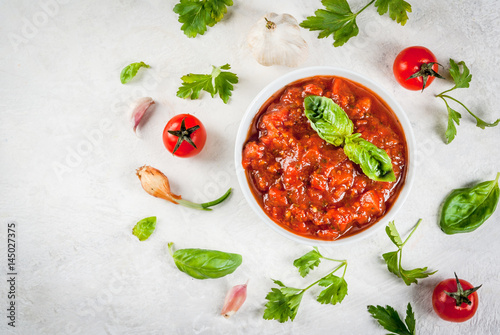 Basic Italian tomato sauce marinara for pasta. In a saucepot with ingredients on a white concrete table. Top view