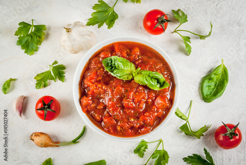 Basic Italian tomato sauce marinara for pasta. In a saucepot with ingredients on a white concrete table. Top view