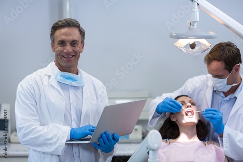 Portrait of dentist holding laptop at dental clinic