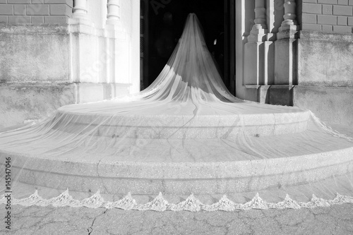 Sposa con velo in primo piano sulle scale entra in chiesa per il suo matrimonio di nozze 