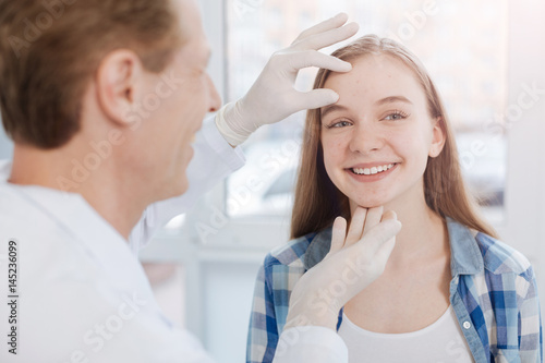 Delighted dermatologist examining patient skin in the hospital