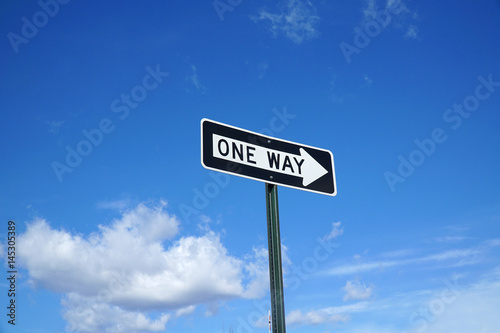 one way sign in front of blue sky and white cloud