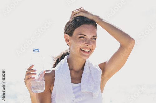 happy sporty woman holding a bottle of mineral water for refreshment