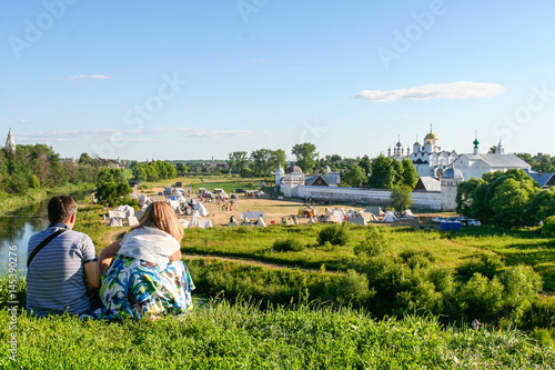 Man and woman look at the Intercession Monastery from the bank of the river Kamenka, Russia, Suzdal