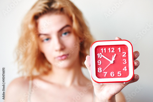 The concept of premature ejaculation men. Girl on a white background holding a red clock closeup