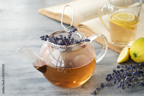 Lavender tea in a glass teapot with book in the background 