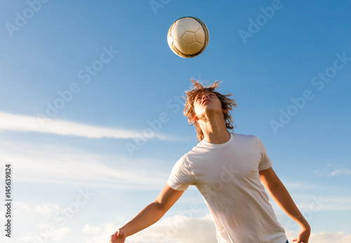Male soccer / football player hitting the ball with his head. 