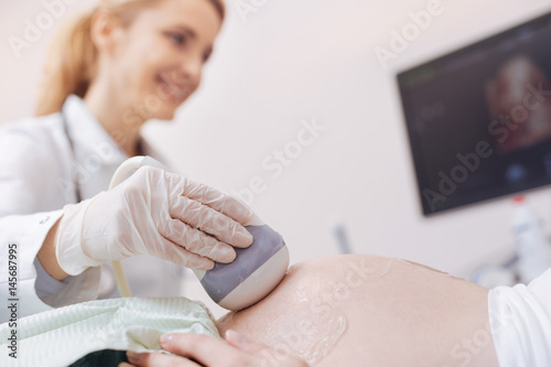 Skillful practitioner enjoying working hours in the sonography cabinet