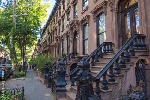 Scenic view of a classic Brooklyn brownstone block with a long facade and ornate stoop balustrades in New York City