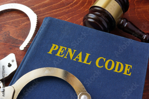 Cuffs and book with the title Penal code. Criminal law concept.