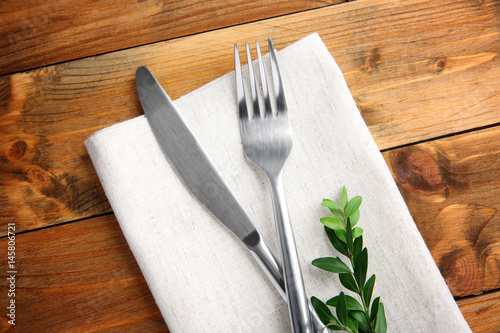 Table setting with silver cutlery and napkin on wooden background