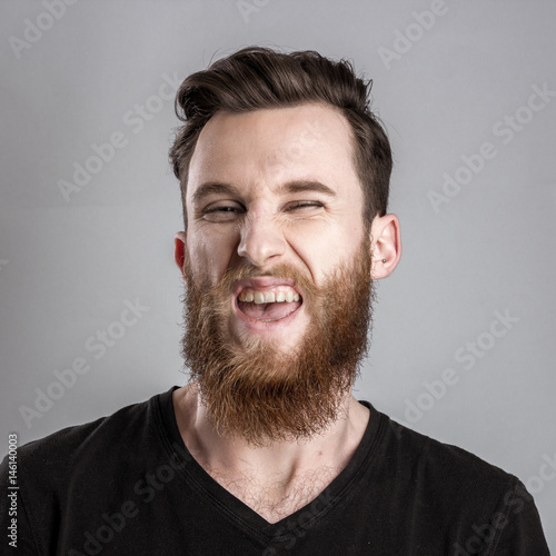 Treacherous and crafty young man isolated on gray background