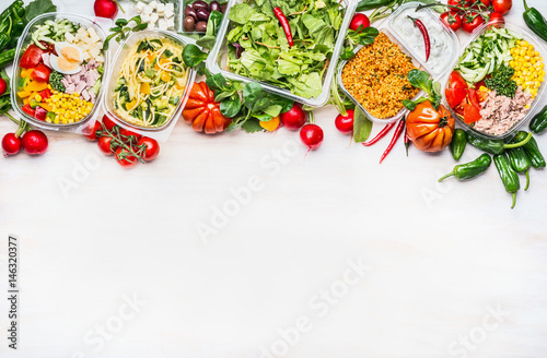 Healthy food concept. Variety of vegetables salad bowls in plastic package on white wooden background, top view, border. Salad bar. Take away Diet lunch ideas