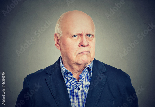 Angry, grumpy senior business man, isolated on gray background