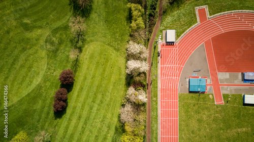 Track and Field. Abstract aerial view looking down onto a professional athletics running track set against the green of a neighbouring golf course.