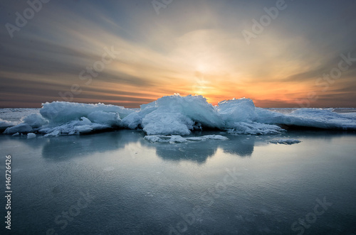 Abstract frozen winter sunrise seascape with ice and colored the sky.