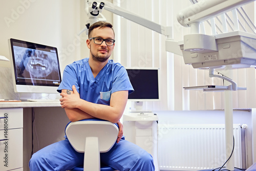 Male dentist in a room with medical equipment on background.