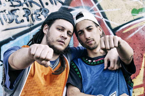 two rap singers in a subway with graffiti in the background