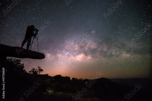 Cameraman takes photo of milky way on Stone lodge under night sky stars