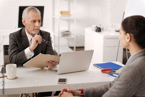 Handsome gray-haired man keeping glasses in right hand