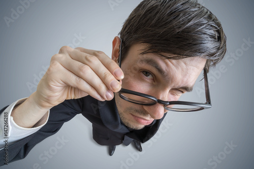 Young skeptic man with glasses is looking at you. View from above.