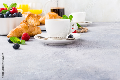 Healthy breakfast with coffee, croissants, fresh berries and orange juice on light gray background, selective focus, copy space.