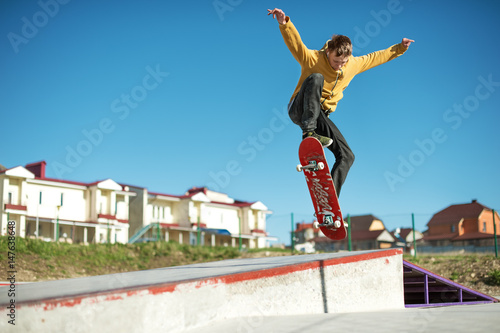 A teenager skateboarder does an ollie trick in a skatepark on the outskirts of the city