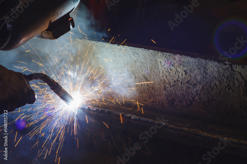 Worker welding steel by MIG/MAG weld (Argon welding) in industrial factory .