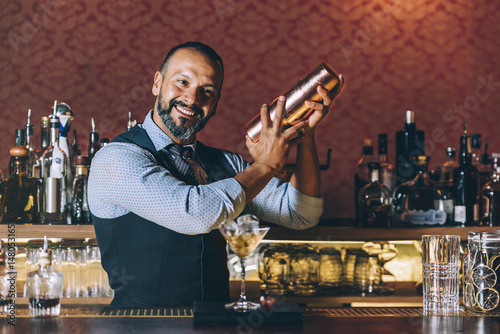 Barman is making cocktail at night club.