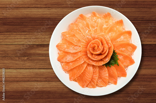 Top view of salmon sashimi serve on flower shape in white ice bowl boat on wood table background, Japanese style.