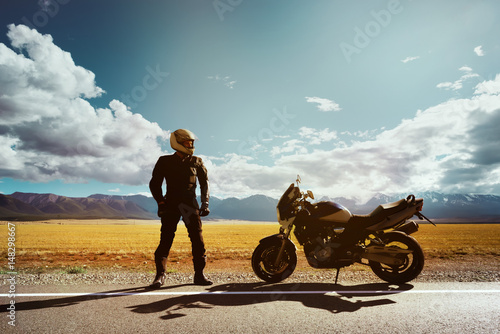 Biker with motorcycle stands on the road