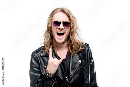 portrait of handsome rocker in black leather jacket and sunglasses showing rock sign isolated on white, rock star concept
