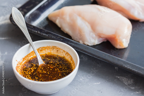 Chicken and ingredients for marinade. Preparing food. Chicken in marinade with herbs and spices. Ready for cooking.