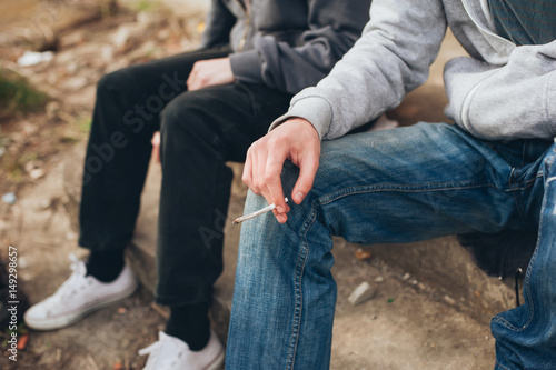 Two friends smoking joint in abandoned ghetto part of city